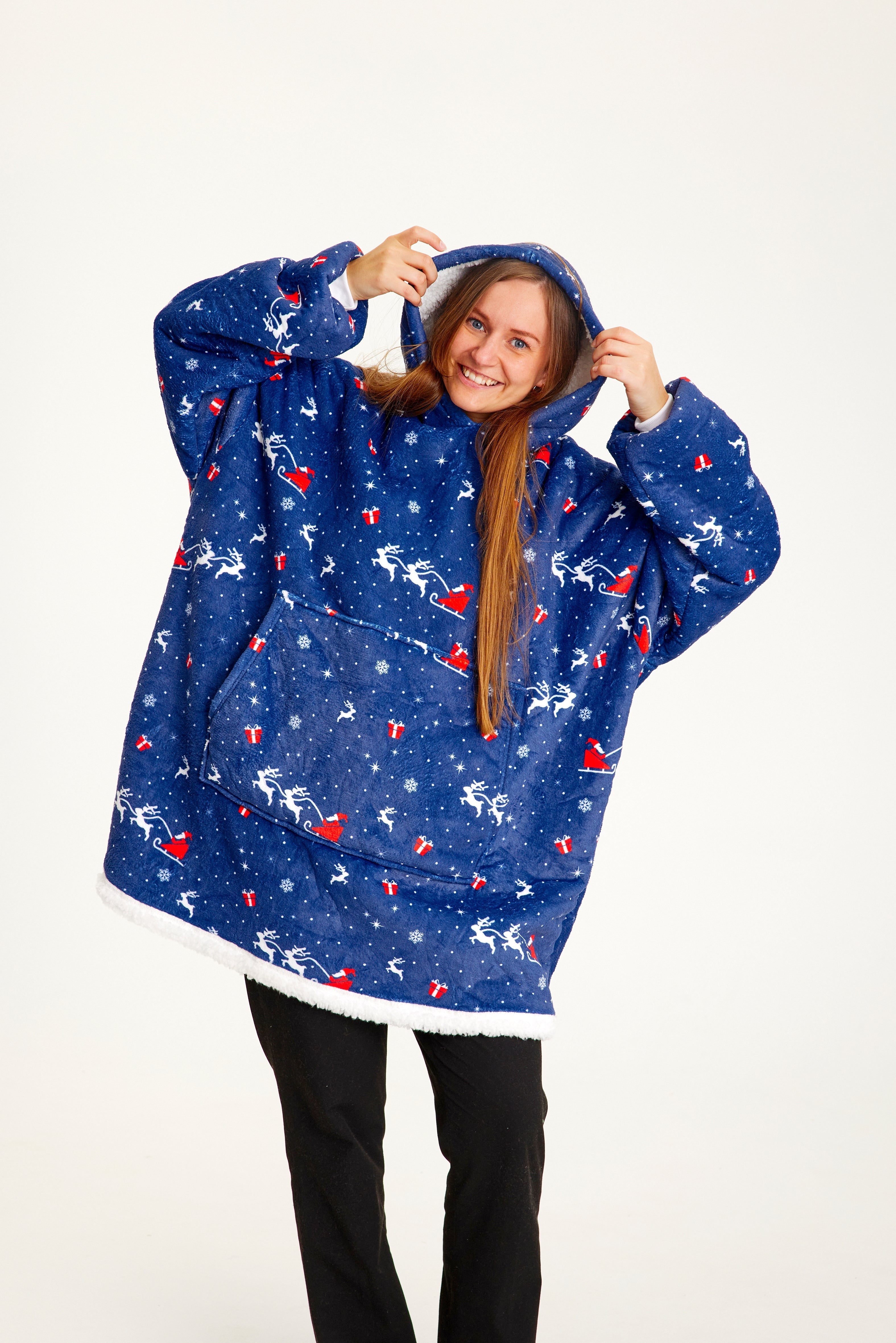 En kvinna som bär en blå julig huvtröja med jultomten och hans släde på.